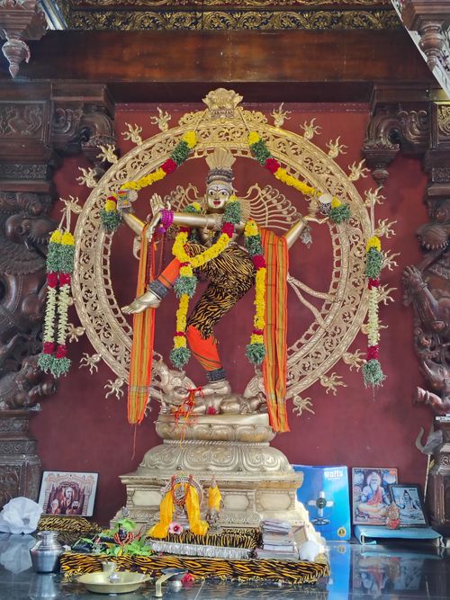 Free Nataraja statue adorned with colorful garlands in a richly decorated temple interior, symbolizing cosmic dance. Stock Photo