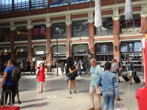 Free Travelers at Amiens railway station showcasing vibrant city life on a sunny summer day. Stock Photo