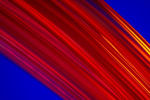 Free A vivid abstract image featuring dynamic red light trails against a blue background. Stock Photo