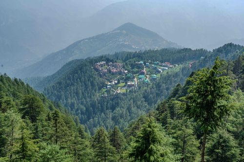 Free Breathtaking aerial view of a lush, forested mountain village with clear sky. Stock Photo
