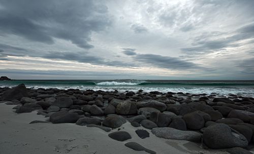 Free Scenic view of a rocky beach under a cloudy sky with waves crashing on the shore. Stock Photo