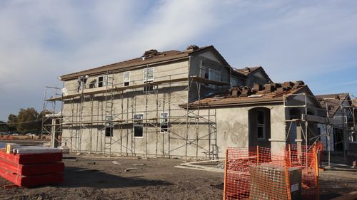 Free Two-story residential building under construction, featuring scaffolding and roof tiles. Stock Photo