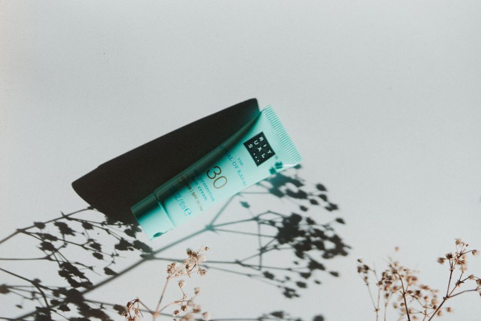 Simple composition of a sun protection cream tube casting botanical shadows, highlighting beauty and skincare.