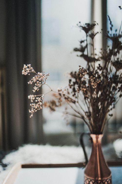 Free Charming dried flowers elegantly arranged in a copper vase on a table with a soft focus background. Stock Photo