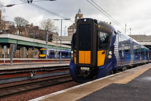 Free A modern train at Edinburgh Waverley Station under a cloudy sky, showcasing urban transit. Stock Photo