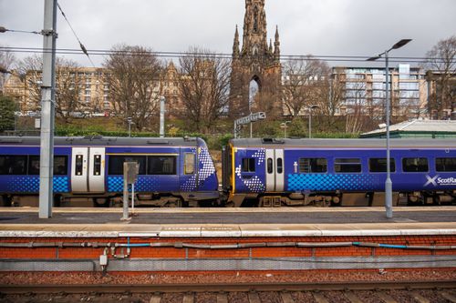 Free ScotRail train captured by the iconic Scott Monument in Edinburgh, highlighting urban transport. Stock Photo