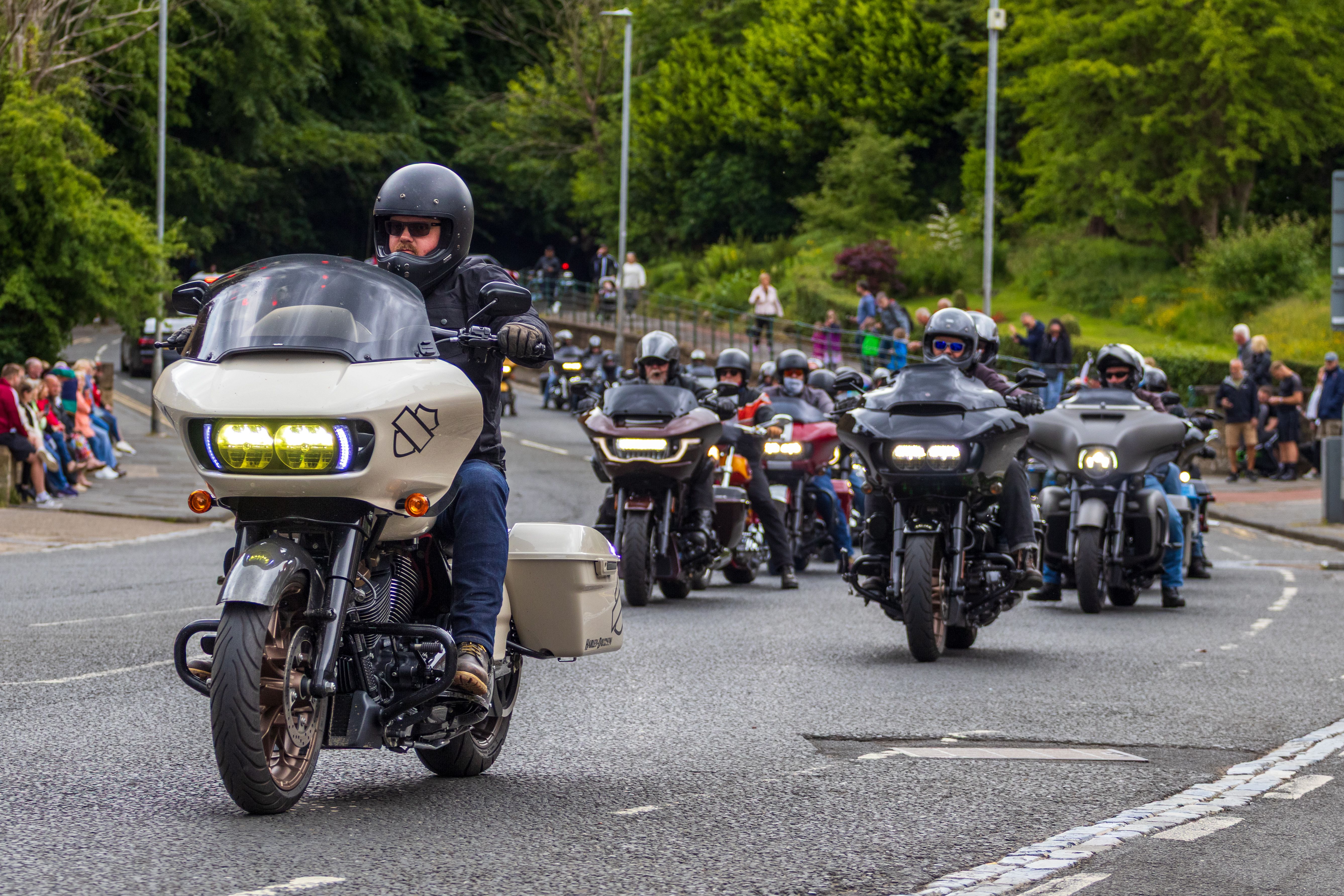 A motorcycle parade with riders in Morpeth, England showcasing various bikes and bikers.