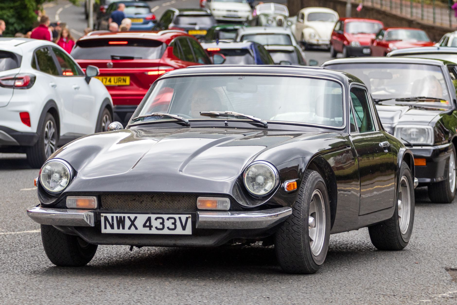 Vintage and modern cars showcased in a parade in Morpeth, England.