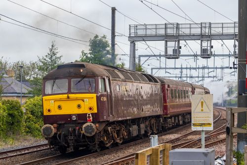 Free A vintage diesel train travels on a curved railway track surrounded by greenery. Stock Photo