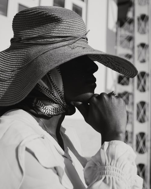 Free Black and white portrait of a fashionable woman wearing a wide-brimmed hat and scarf outdoors. Stock Photo