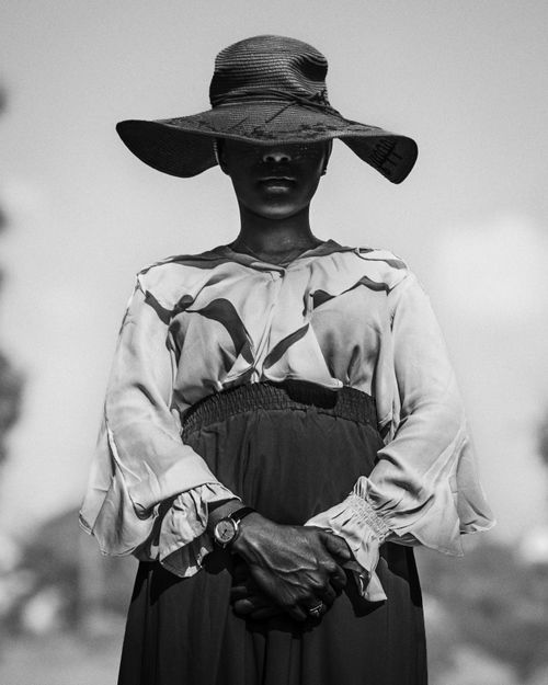 Free Black and white portrait of an elegant woman wearing a wide-brimmed sun hat with folded hands. Stock Photo