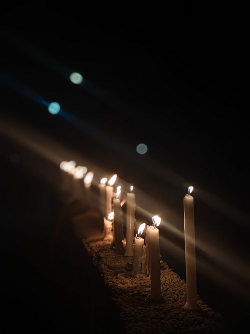 Free A row of lit candles casting a warm glow in the darkness, creating a peaceful ambiance. Stock Photo