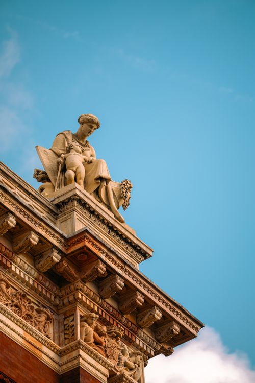 Free Close-up of a classical statue on a historic London building against a clear blue sky. Stock Photo