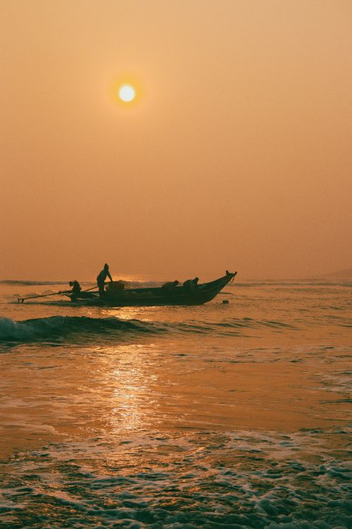 Free Silhouette of fishermen rowing a boat at sunrise, reflecting on calm waves, evokes tranquility and adventure. Stock Photo
