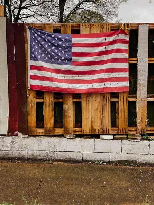 Free USA flag displayed on a rustic wooden fence outdoors, showcasing patriotic spirit. Stock Photo
