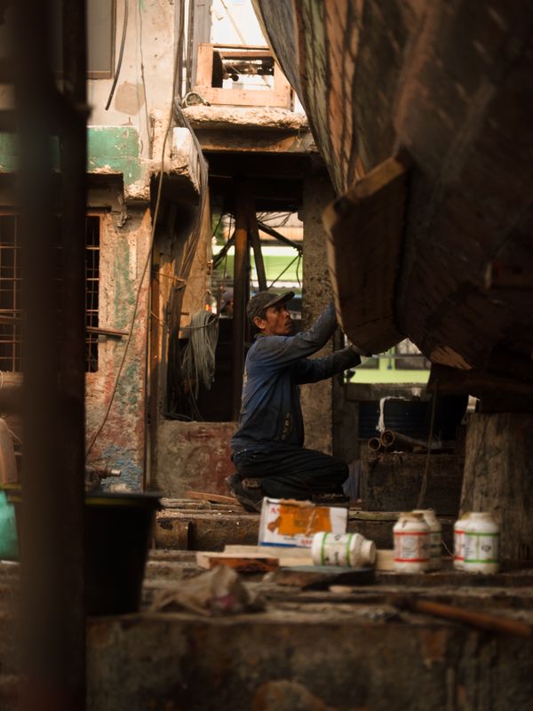 A man repairing a wooden boat in a yard