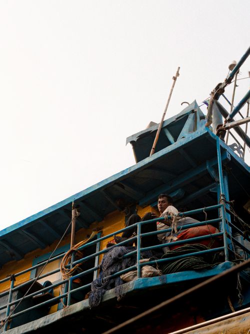 Free View of fishermen working aboard a colorful boat at sea, showcasing maritime life. Stock Photo