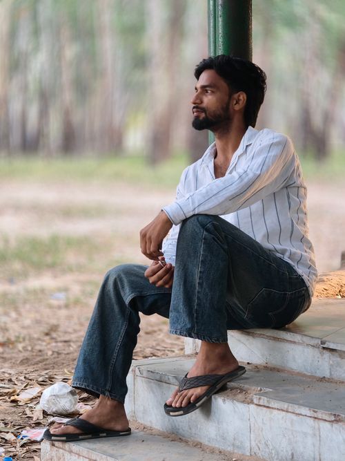 Free A man in casual attire is sitting thoughtfully outdoors on steps. Stock Photo