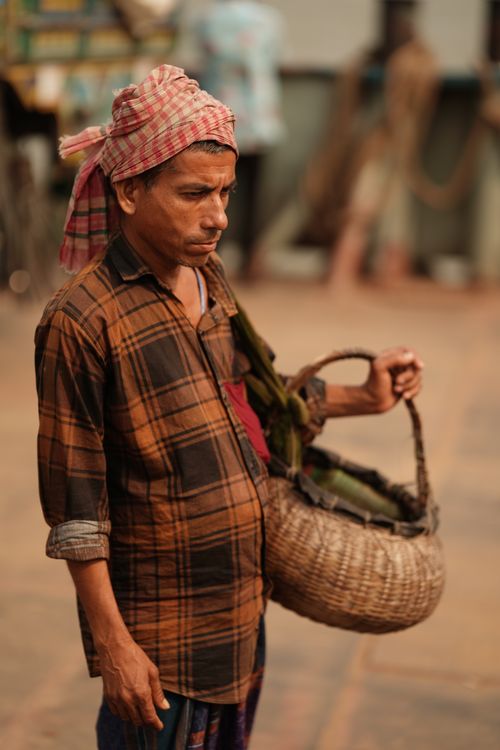 Free Man wearing traditional attire holding a woven basket outdoors. Stock Photo