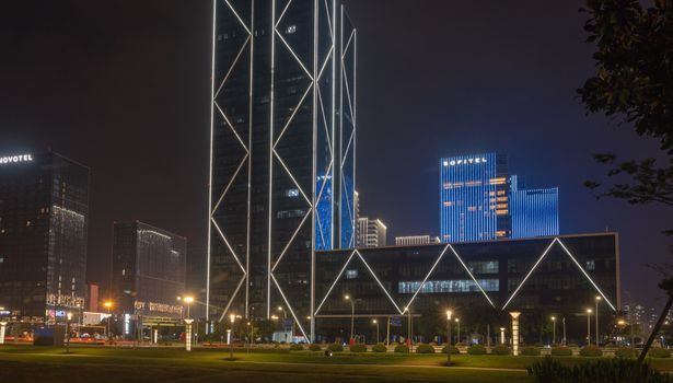 A cityscape featuring modern skyscrapers illuminated during nighttime showcasing urban architecture.