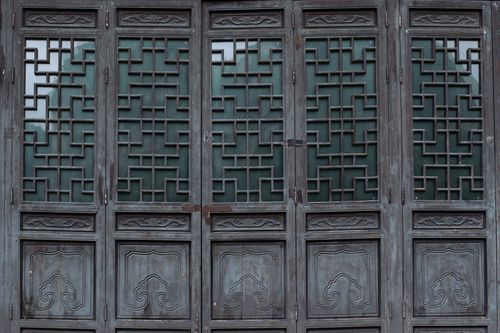 Free Close-up of a traditional Asian wooden door featuring intricate geometric patterns and carvings. Stock Photo