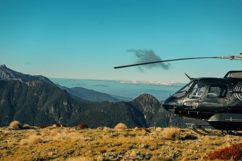 Free Helicopter landing on a picturesque mountain terrain under a clear blue sky. Stock Photo