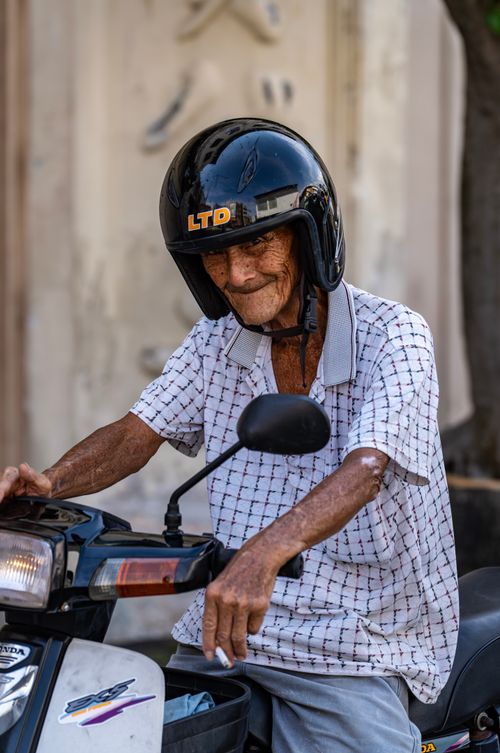 Free Senior man on a motorcycle wearing a safety helmet, captured outdoors in Malaysia. Stock Photo