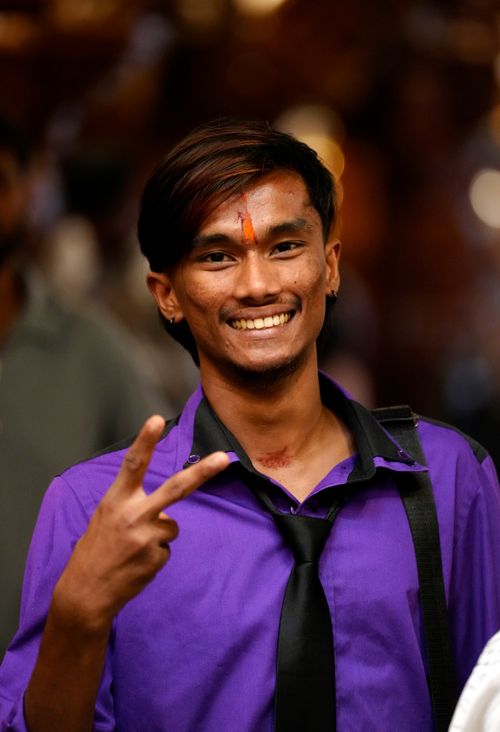 Free Smiling young man in vibrant attire showing peace sign, capturing joy in Malaysia. Stock Photo