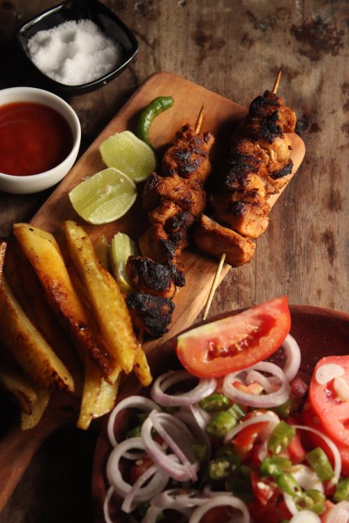 Free Delicious grilled chicken skewers with a side of fresh salad, fries, and dips. Stock Photo
