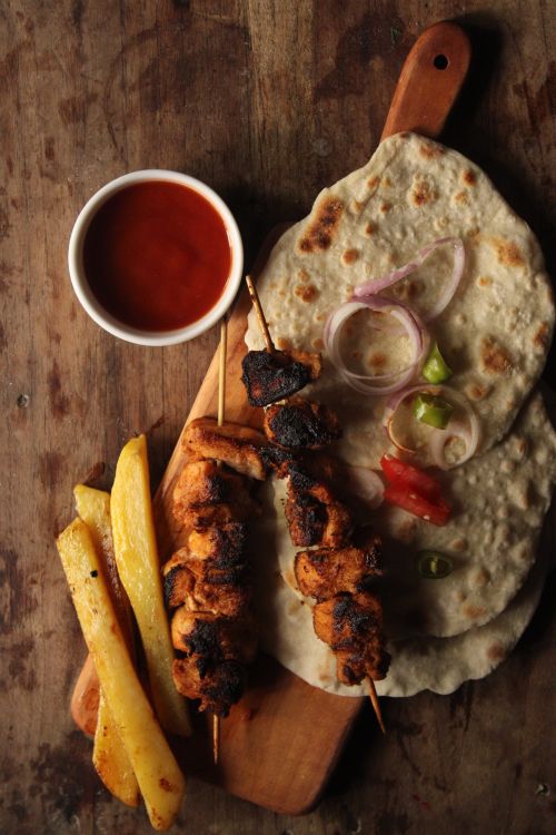 Free Top view of grilled chicken skewers with naan bread, fries, and sauce. Stock Photo