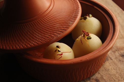 Free Close-up of Indian sweets in a traditional clay pot, garnished with nuts and saffron. Stock Photo