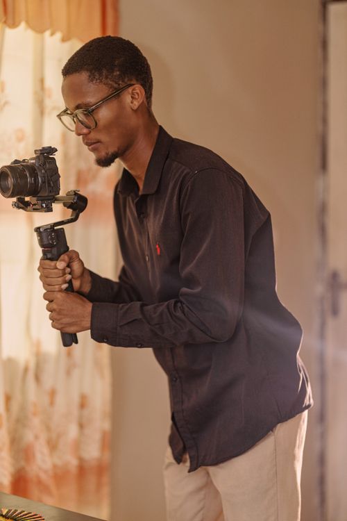 Free Male photographer using a stabilizer indoors with warm lighting. Stock Photo