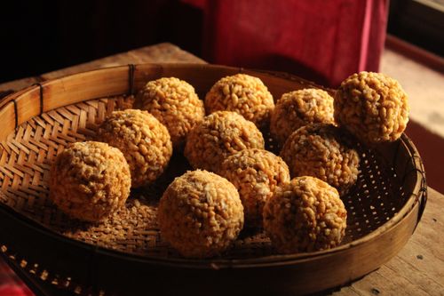 Free Golden Ladoos arranged on a rustic woven tray, bathed in warm light. Stock Photo