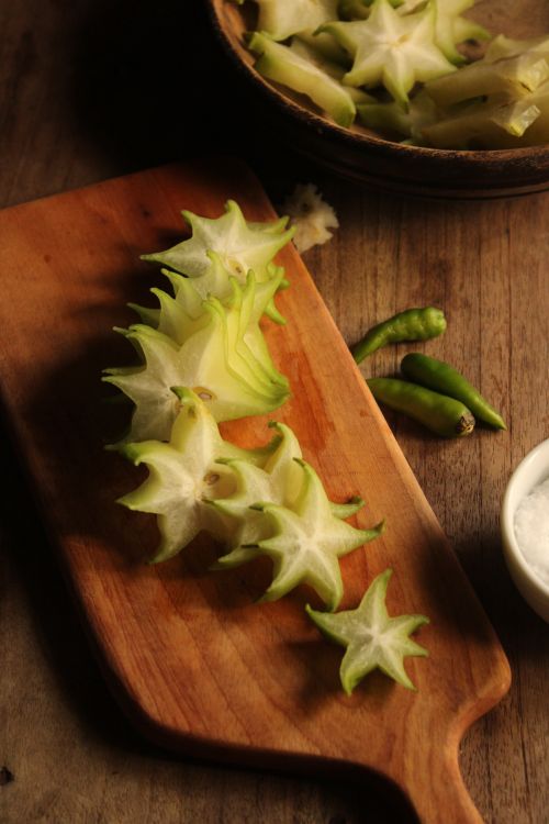 Free Freshly sliced starfruit on a wooden board with green chilies. Stock Photo