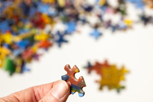 Focus on a colorful puzzle piece held by a hand with blurred pieces in the background.