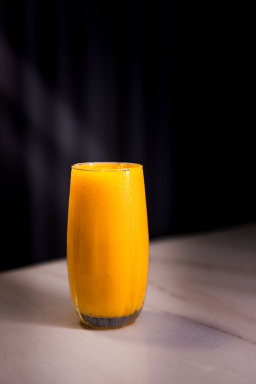 Free A tall glass of vibrant orange juice placed on a marble surface, ideal for refreshment. Stock Photo