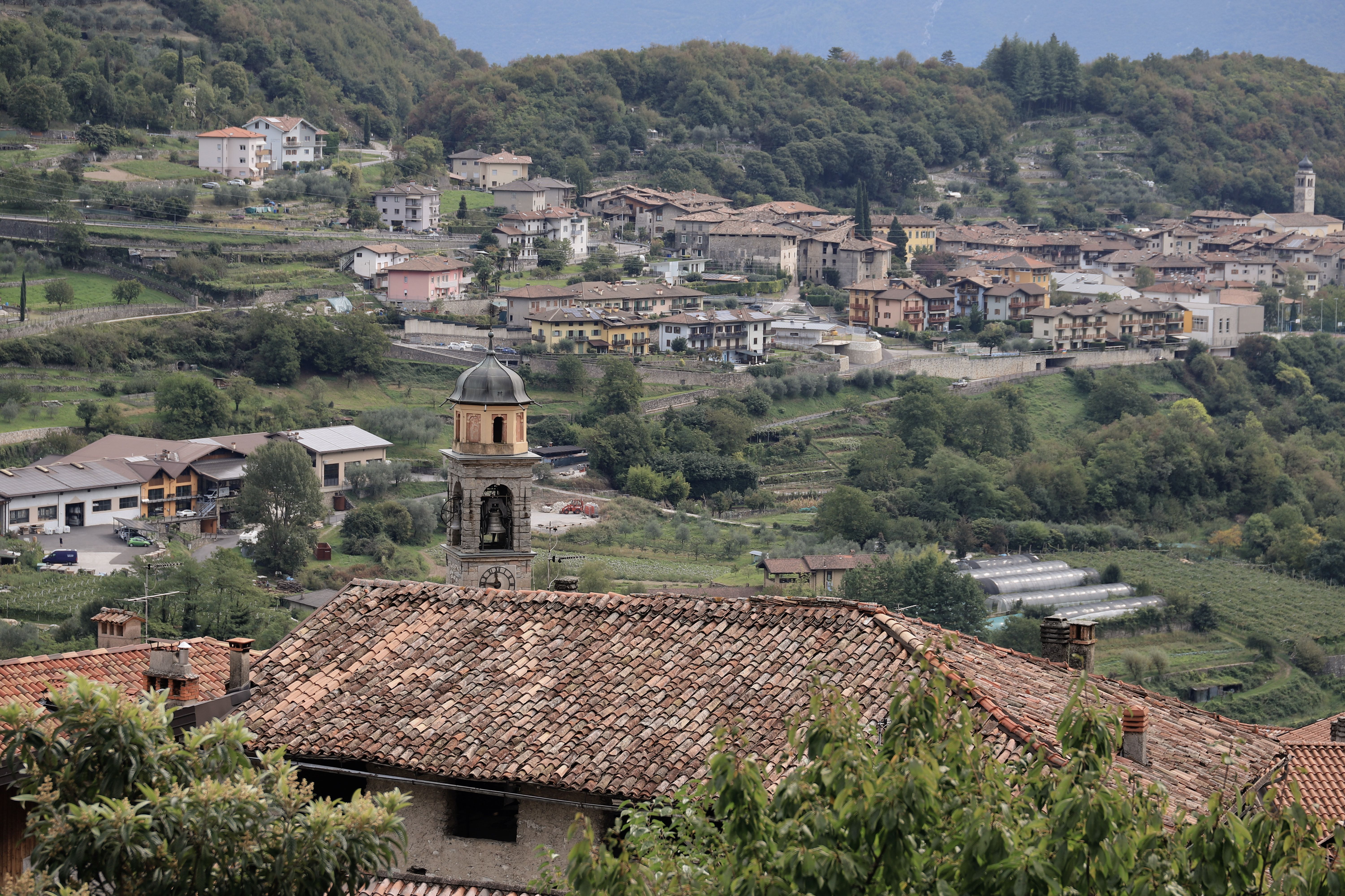 Beautiful overlook of a picturesque Italian village with a church steeple surrounded by lush greenery and rolling hills.