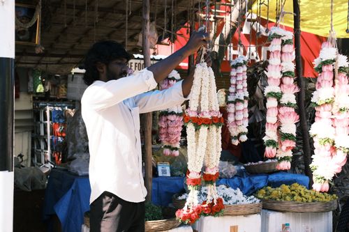 Free Male vendor arranging flower garlands at a market stall in Bengaluru, India. Stock Photo