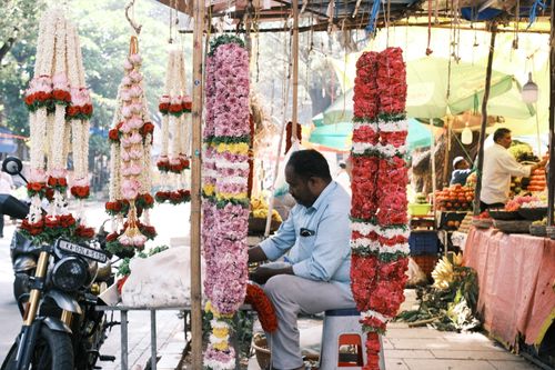 Free A colorful market stall in Bengaluru featuring vibrant flower garlands and a vendor. Stock Photo