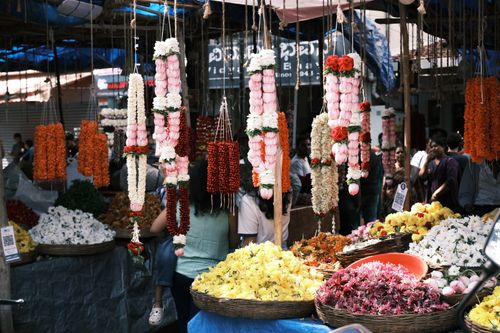 Free Colorful hanging garlands and flowers for sale at a bustling Bengaluru market. Stock Photo