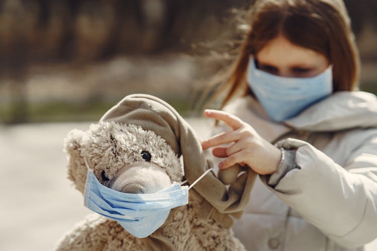 Girl With A Face Mask Playing With Teddy Bear