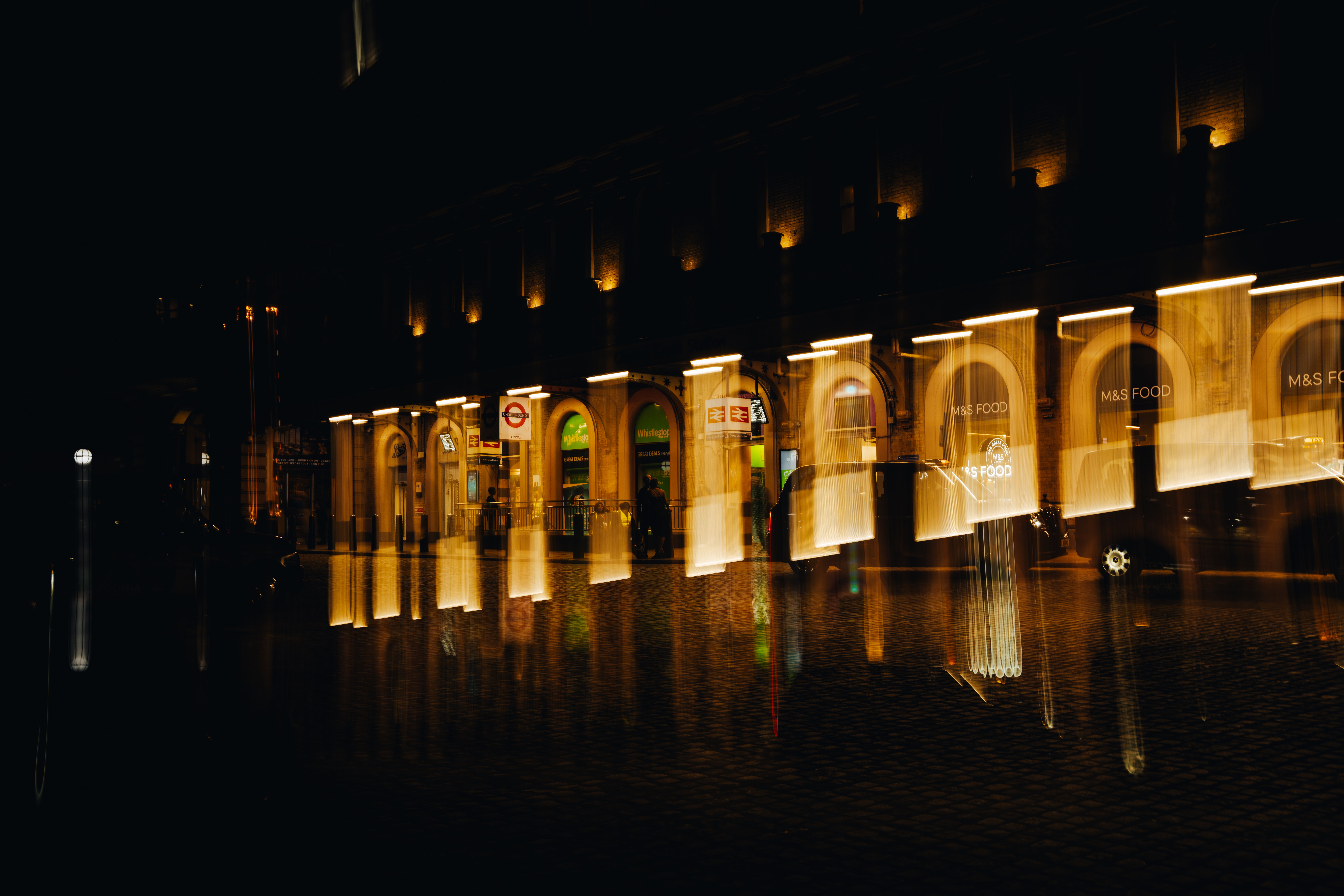 Creative panning shot capturing illuminated arcade at night in London, England.