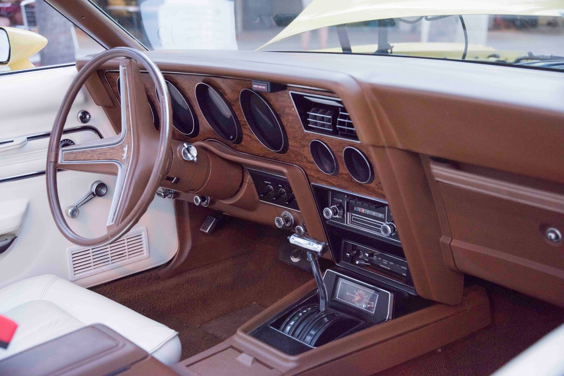 Vintage car interior showcasing wood trim dashboard and steering wheel.