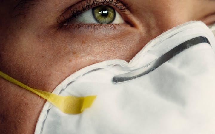 Detailed image of a person's eye and protective face mask, representing health safety.