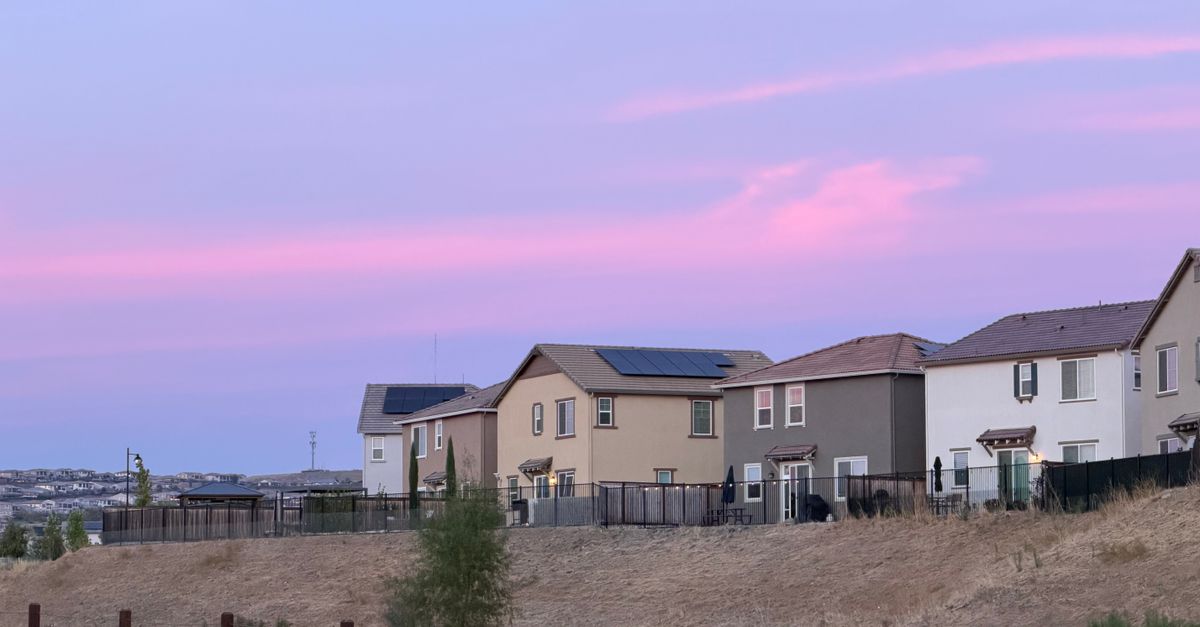 Charming suburban neighborhood with a vibrant pink sky at sunset, highlighting modern homes.