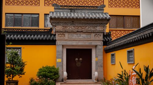Free Ornate traditional Chinese stone gateway with vibrant yellow walls and intricate roof design. Stock Photo
