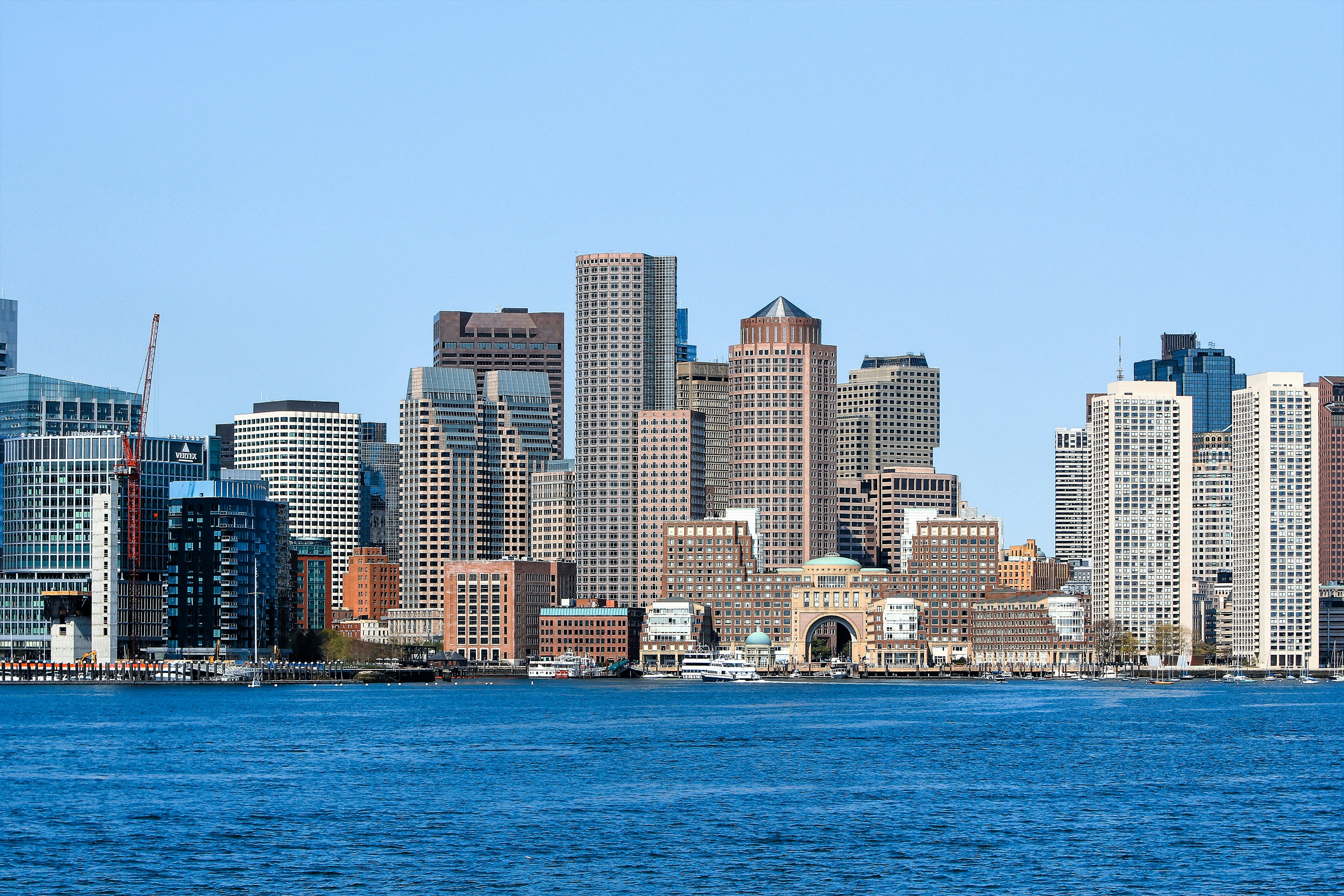Panoramic view of Boston skyline with skyscrapers and waterfront under a clear blue sky.