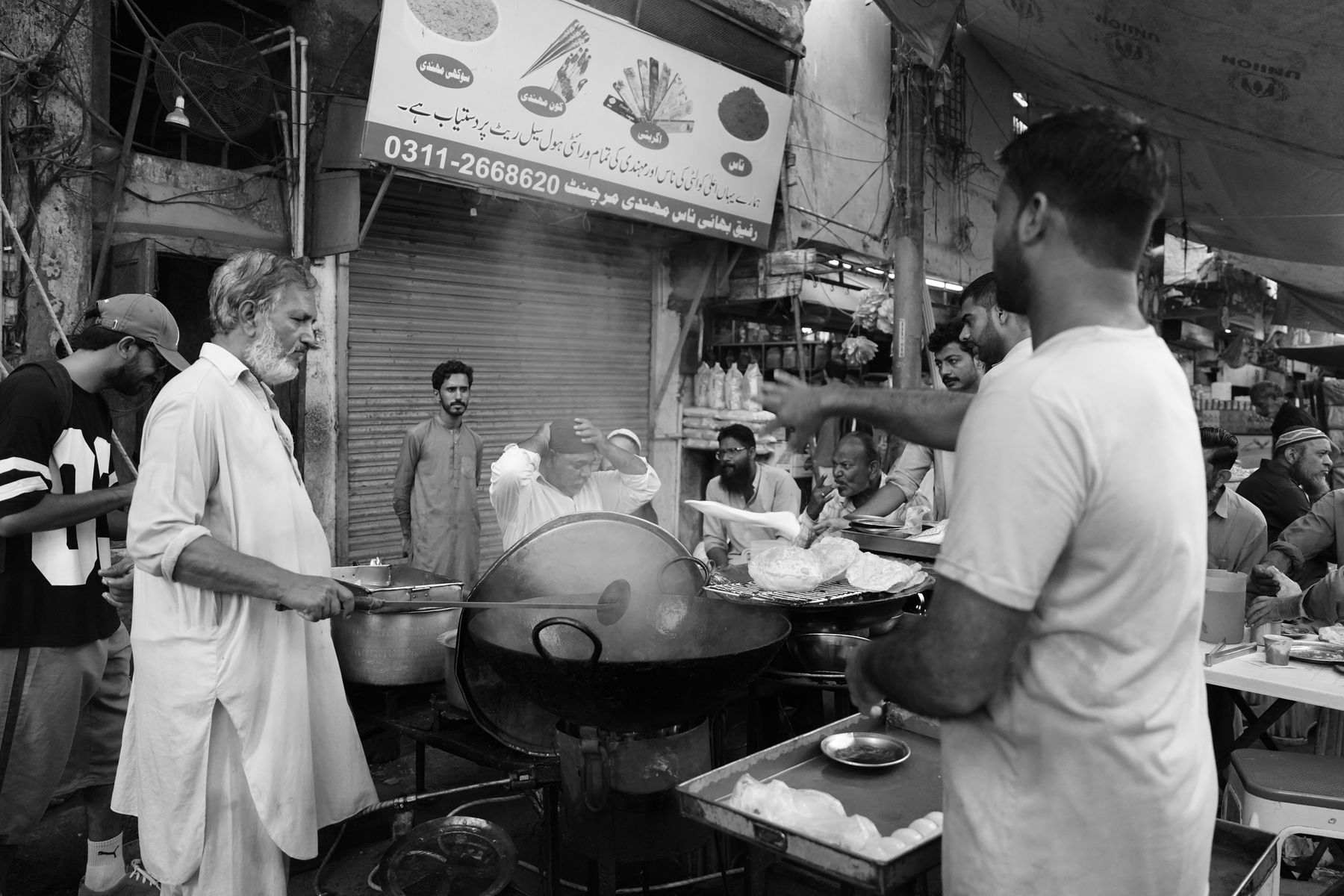 Chefs cooking at an outdoor street food stall in Pakistan, capturing daily life.
