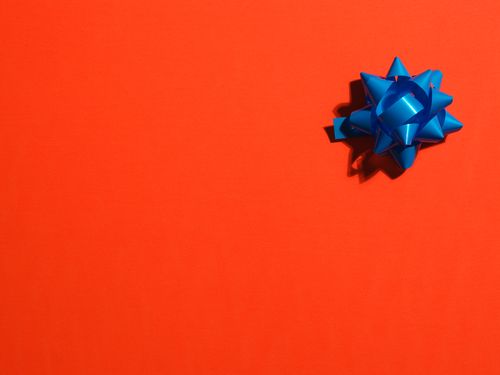 Free A striking image of a blue gift bow on a bright orange background, ideal for celebrations. Stock Photo