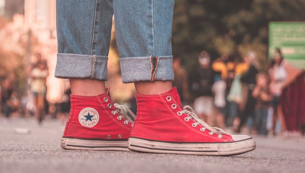 A close-up of red canvas sneakers on a street, capturing urban style and casual footwear fashion.